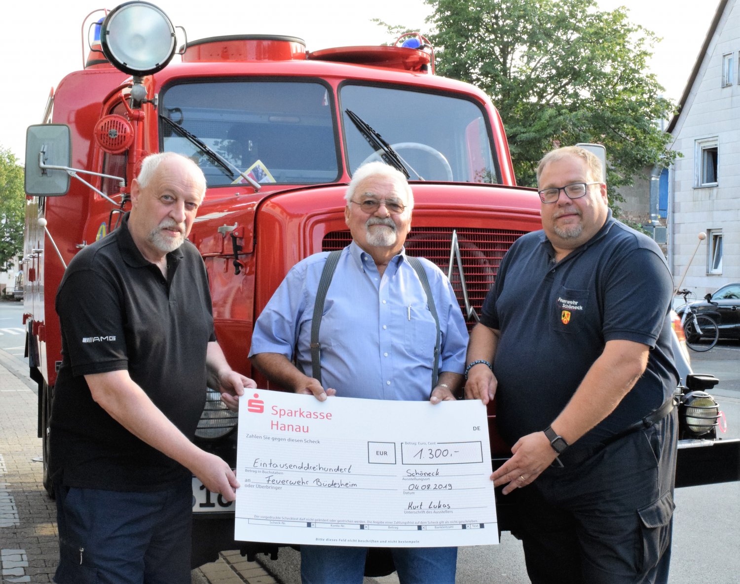 Von links: Kassenwart Jürgen Hof, Alters- und Ehrenmitglied Kurt Lukas und Wehrführer Thomas Walter bei der symbolischen Scheckübergabe vor dem Oldtimer Tanklöschfahrzeug der Büdesheimer Wehr.