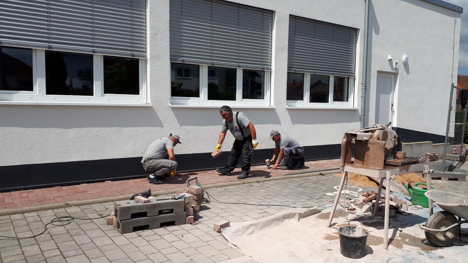 Bauarbeiter verlegen derzeit die letzten Pflastersteine im Außenbereich der Mehrzweckhalle Mittel-Gründau, die in neuem Glanz erstrahlt.