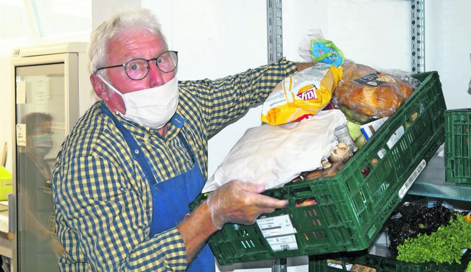 Bernd Ries bringt einen Lebensmittelkorb zu den Kunden. Männliche Helfer stehen bei der Tafel hoch im Kurs