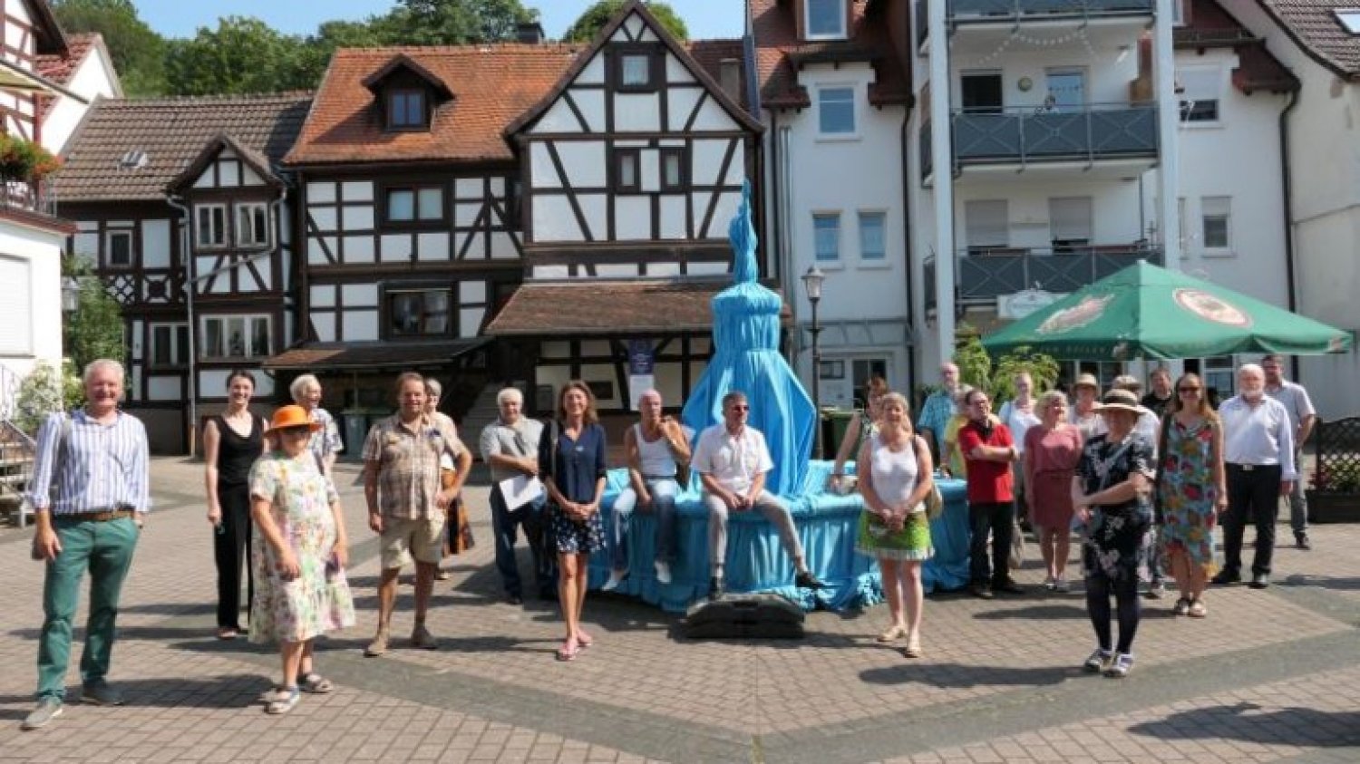Bürgermeister Andreas Weiher (links) mit den Künstlern am verhüllten Wächterbrunnen