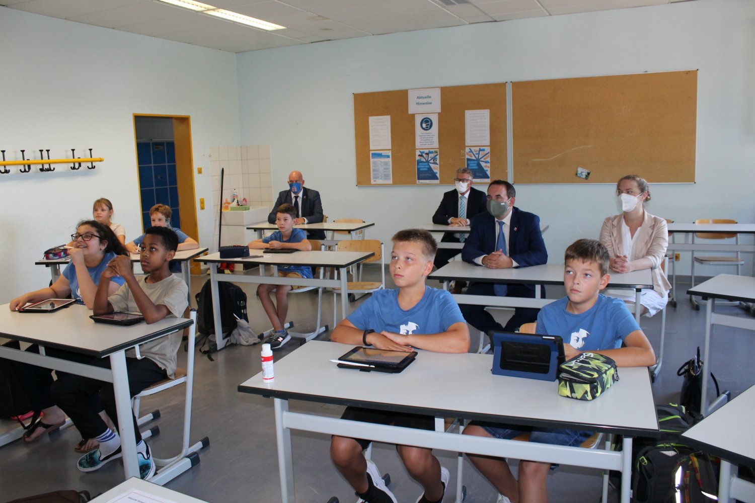 Digitalisierter Deutschunterricht: Kreisbeigeordneter Winfried Ottmann (hintere Reihe rechts) und Kultusminister Prof. Dr. Alexander Lorz (mittlere Reihe) lassen sich von Schulleiterin Tina Ruf und ihrem Lehrerteam Beispiele in einer iPad-Klasse zeigen