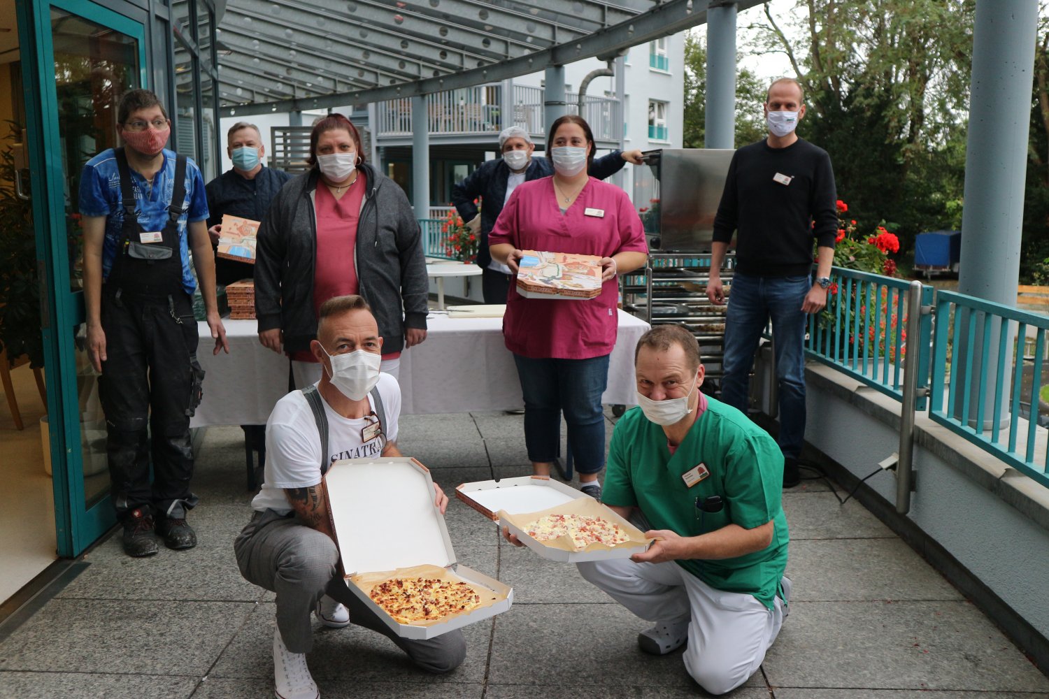 Stephan Hemberger (zweite Reihe rechts), Wolfgang Christoffel (hintere Reihe rechts), Siegfried Rakoczy (hintere Reihe links) und Mitarbeiter*innen aus Pflege, Haustechnik und Betreuung beim Flammkuchen-Stand
