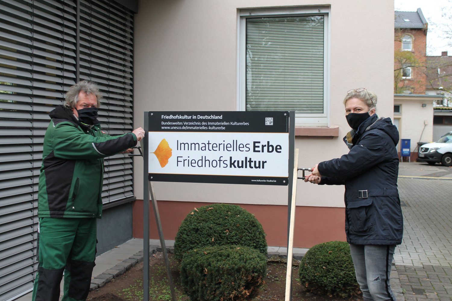 Alexandra Kinski und Thomas Asbach haben den Hinweis auf das 'Immaterielle Erbe' deutlich sichtbar an der Friedhofsverwaltung anbringen lassen.