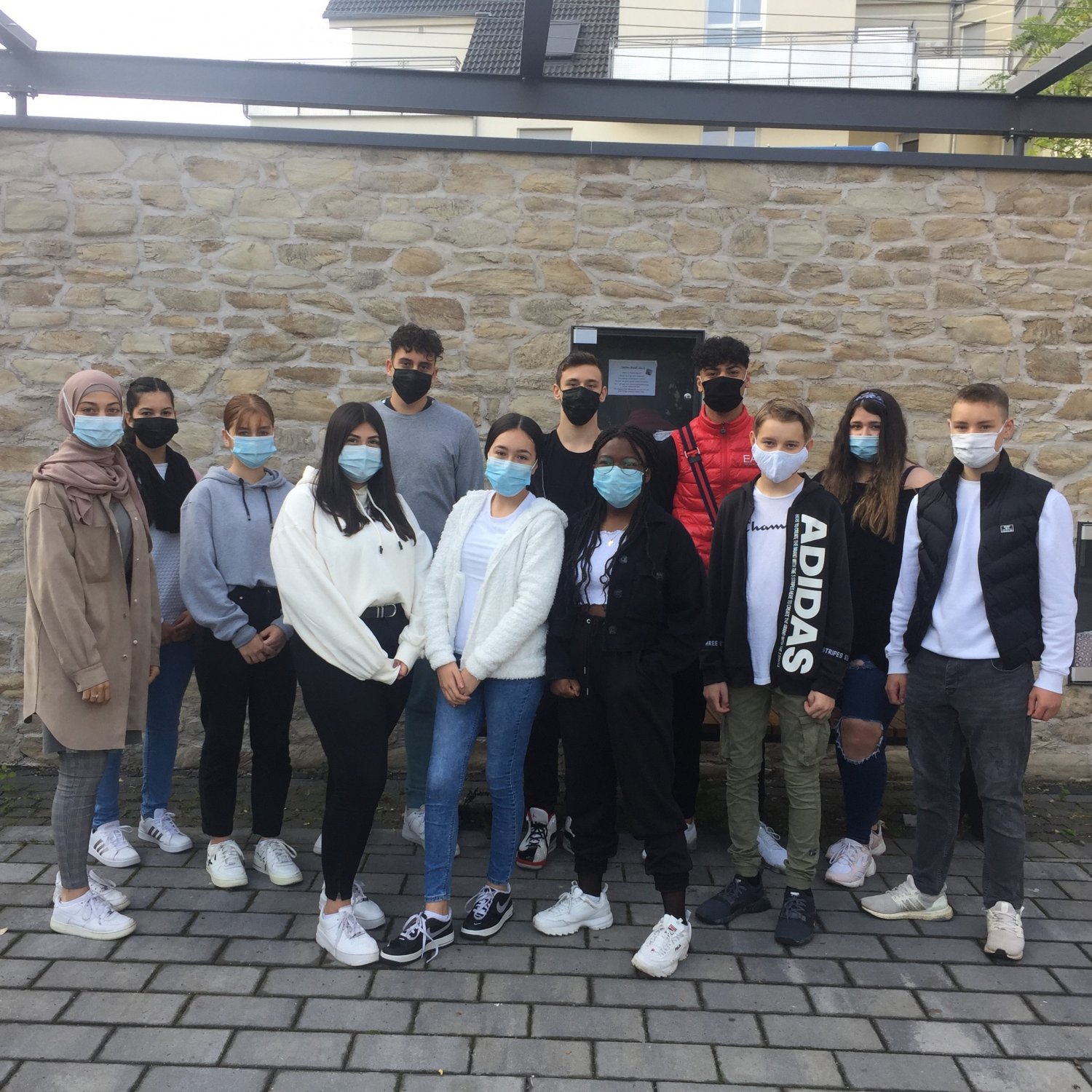 Kunstschüler:innen der Erich-Kästner-Schule vor einem Schaukasten am alten Bischofsheimer Dorfbrunnen.
