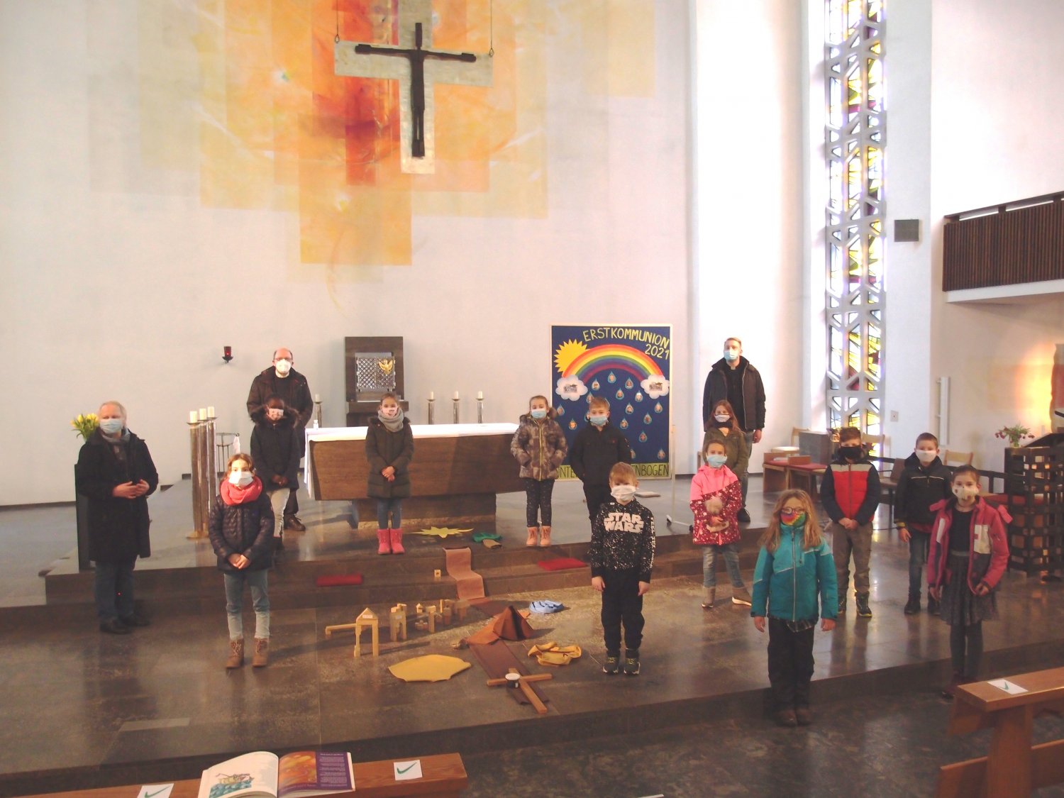 Der Vorfreude tut die aktuelle Corona-Situation keinen Abbruch: Das Foto zeigt einige Kesselstädter Kommunionkinder mit Abstand und Maske am Altar der Kirche. Ihre Fotos erinnern in der Gemeinde an den Schutz Gottes, unter dem sie stehen.