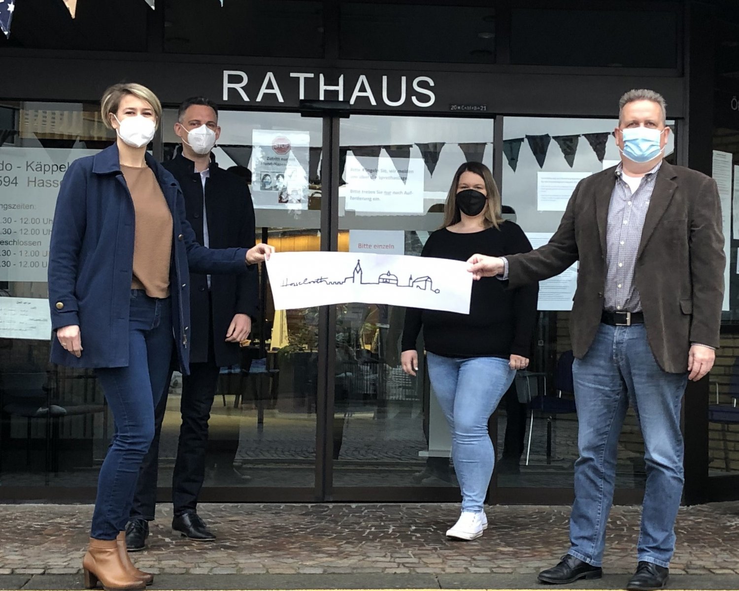 Von links: Theresa Franz und Ehemann, Nadine Herbst, Leitung Finanzen, IT und Digitalisierung und Bürgermeister Matthias Pfeifer mit dem neuen Logo der Gemeinde Hasselroth