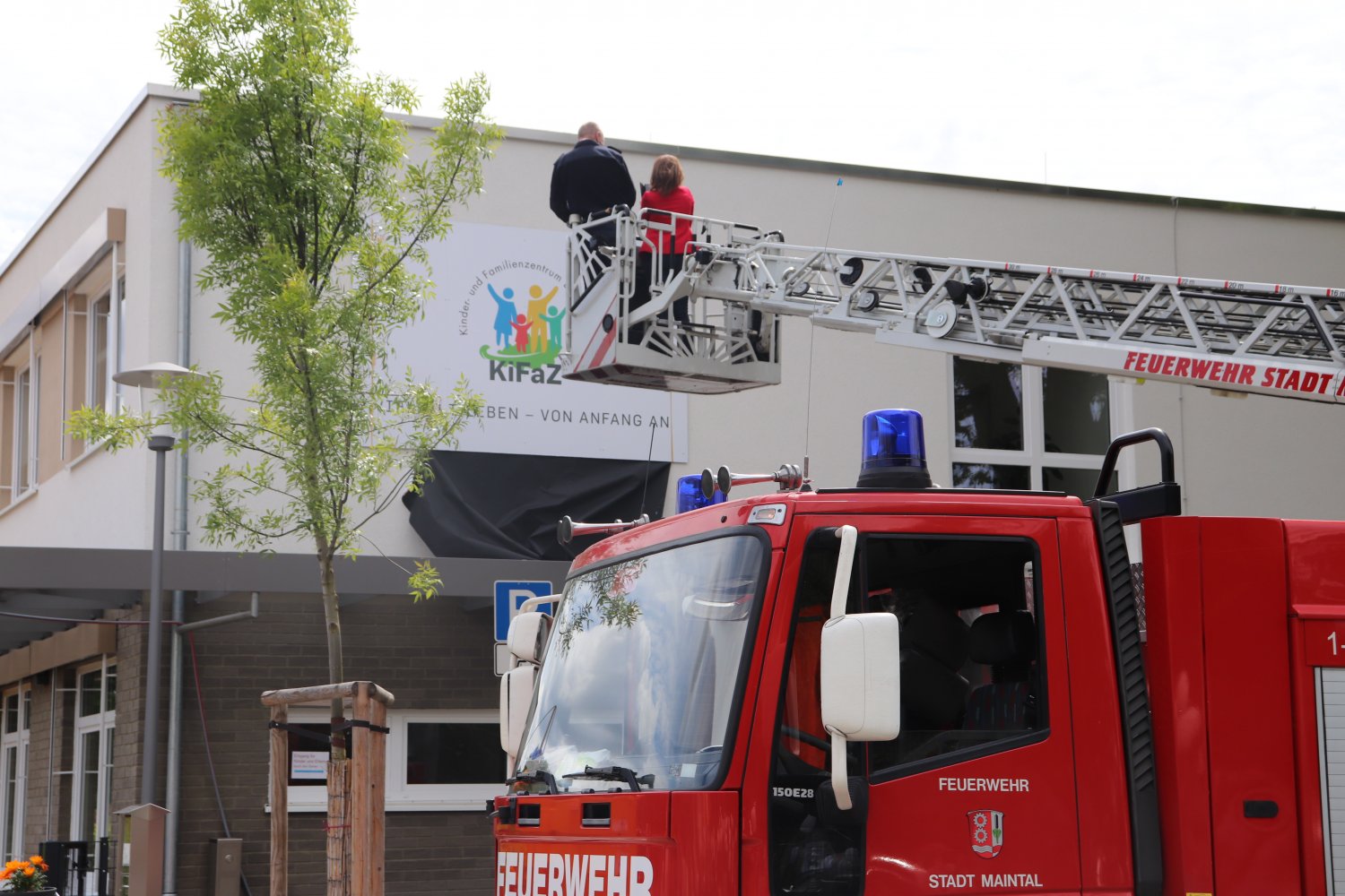 Von der Drehleiter der Freiwilligen Feuerwehr Dörnigheim aus enthüllte Bürgermeisterin Monika Böttcher das neue Hausschild des Kinder- und Familienzentrums Eichenheege.