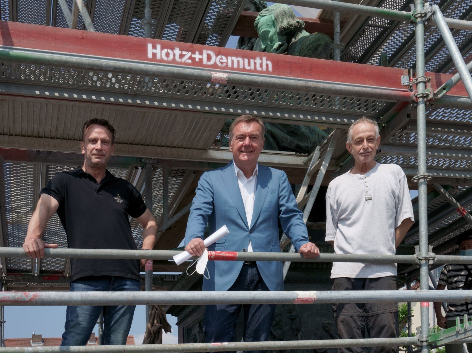 Oberbürgermeister Claus Kaminsky machte sich im Gespräch mit Restaurator Eberhard F. Gutberlet (rechts) sowie Glocken- und Kunstgießer Fritz Georg Rincker (links) ein Bild von den Sanierungsarbeiten am Brüder-Grimm-Denkmal.