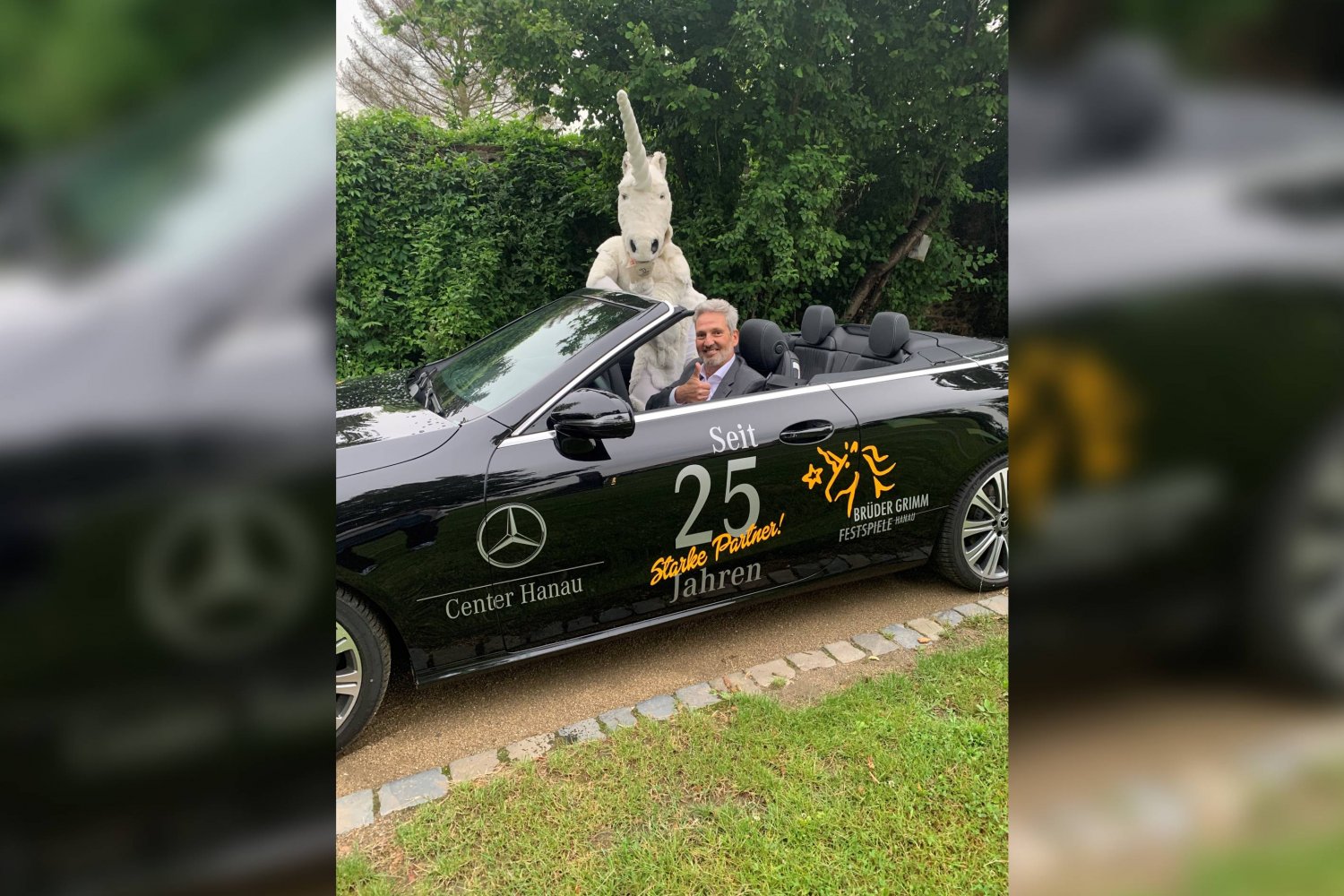 Stefan Scheuermann, Betriebsleiter des Mercedes-Benz-Standortes Hanau in der Moselstraße, und das Einhorn, Maskottchen der Brüder Grimm Festspiele, freuen sich über das 25. Jahr der Partnerschaft.