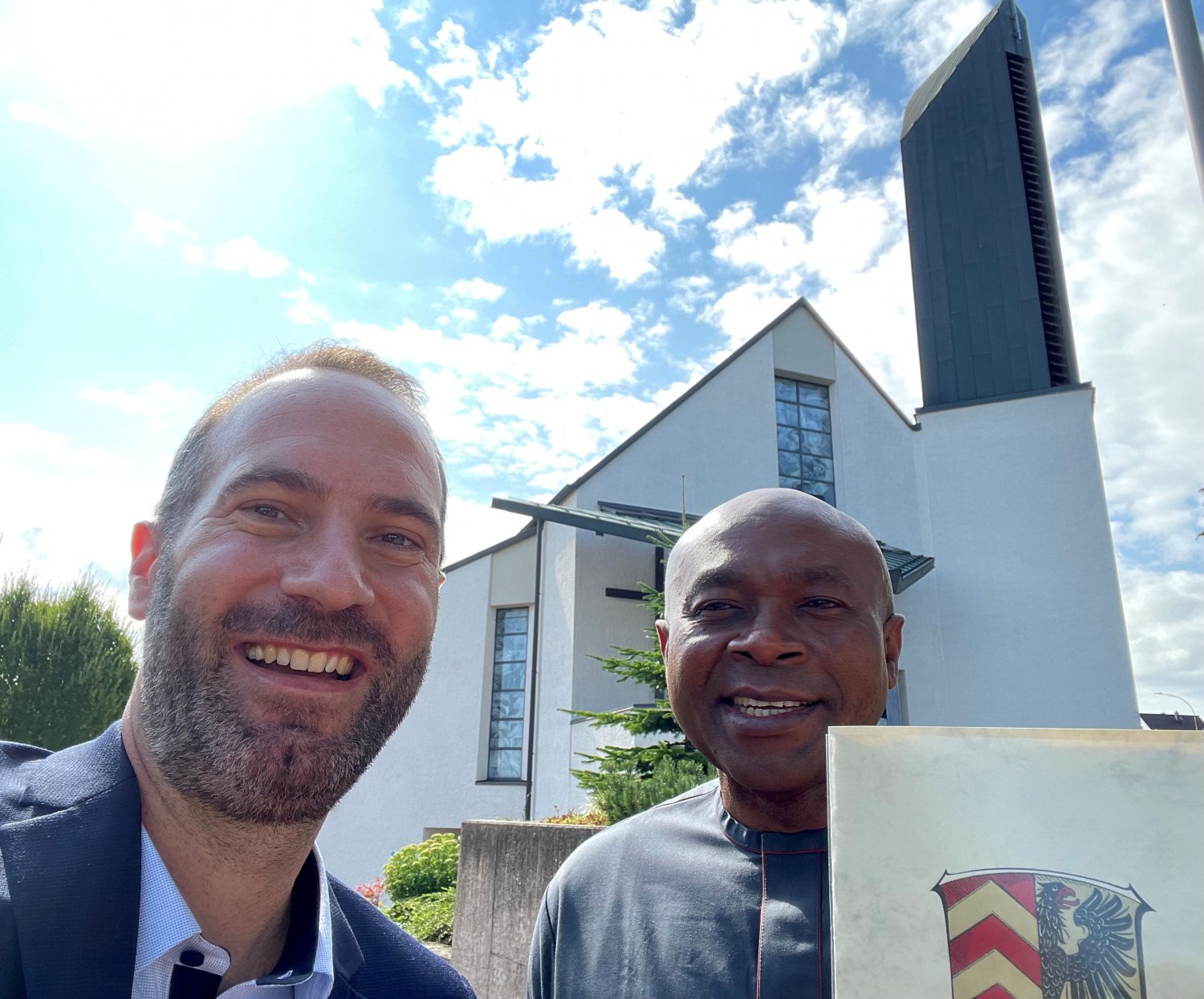Bürgermeister Andreas Bär (r.) gratuliert Pfarrer Dr. Ifeanyi Emejulu (l.).