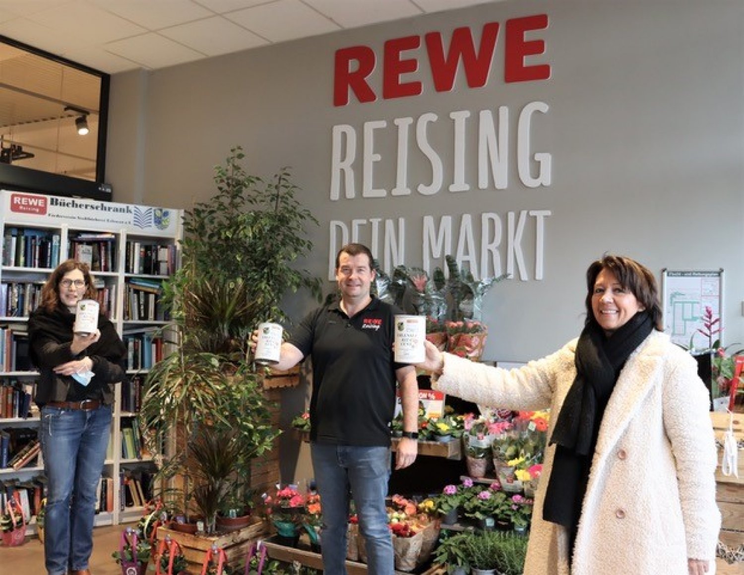 Erste Stadträtin Birgit Behr (r.) und Kathrin Smola-Peter (Fachbereich Familie und Soziales) überreichen die KiTa-CentSammeldosen an Michael Reising.