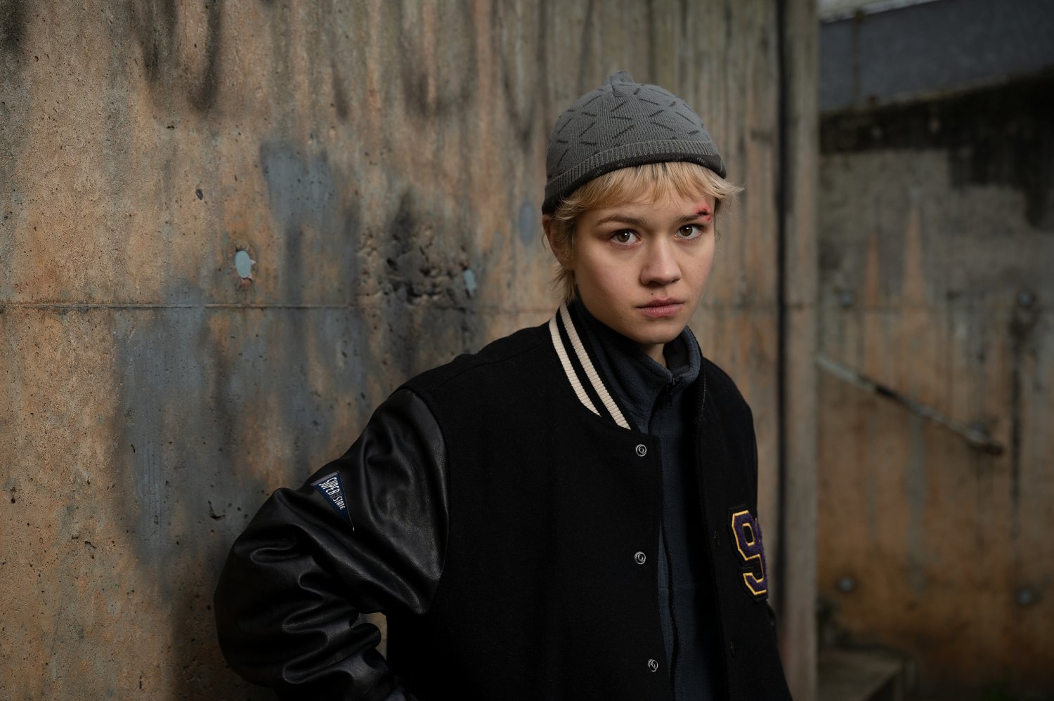 Charlie (Lea Drinda) steht vor einer grauen Steinwand