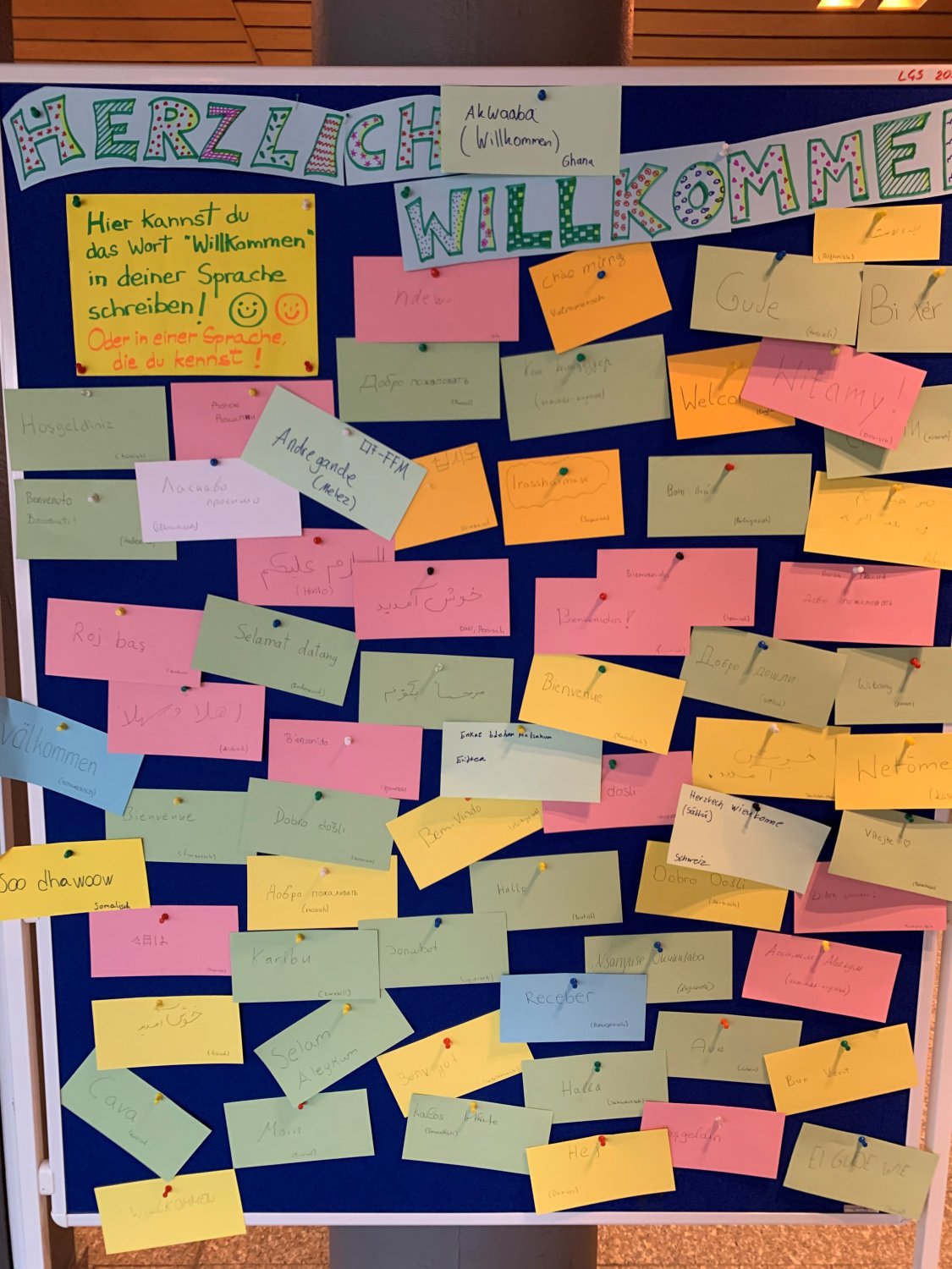 Das Wort „Willkommen“ in vielen Sprachen, von Schülerinnen und Schülern der LGS auf Zettel geschrieben und auf einer Pinnwand am Eingang zum Gedenkraum aufgestellt, brachte die Vielfalt und das friedliche Miteinander an der LGS zum Ausdruck.