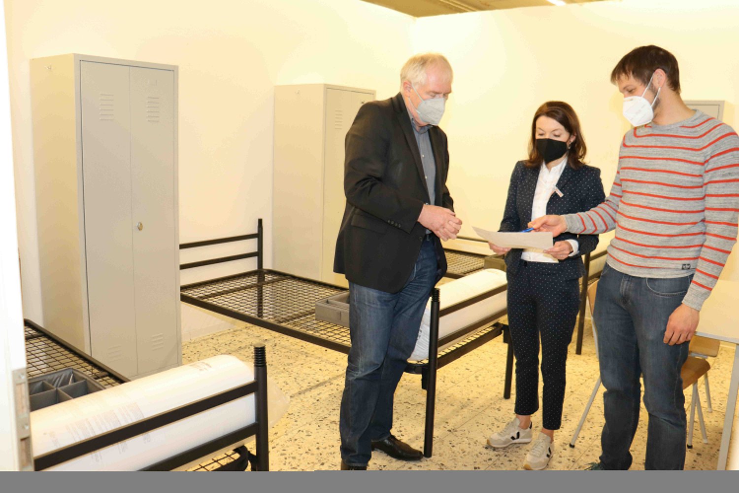 Thorsten Buld, Leiter des Fachdienstes Asyl (rechts), führt Bürgermeisterin Monika Böttcher und Ersten Stadtrat Karl-Heinz Kaiser durch die Notunterkunft in der Carl-Zeiss-Straße.