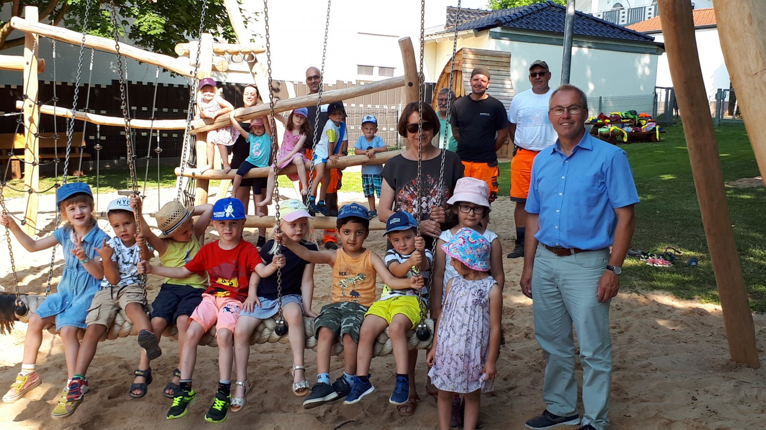 Bürgermeister Helfrich (re.) zusammen mit Kindern und Erzieherinnen der Kita Farbkleckse und Mitarbeitern des ausführenden Bauhofes bei der Einweihung des neuen Spielareals..