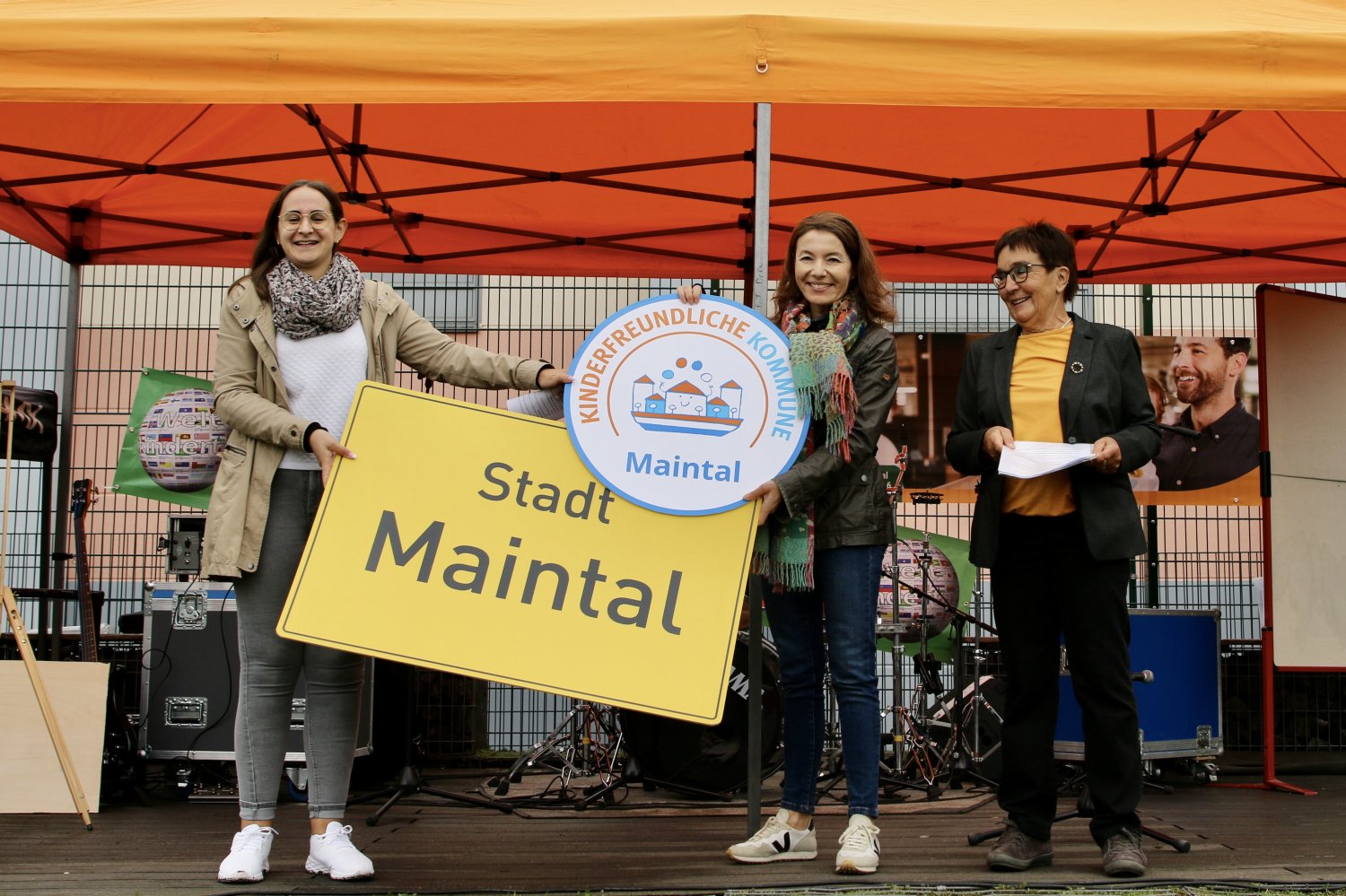 Bürgermeisterin Monika Böttcher (Mitte) und Sara Eckerlin (links) vom Maintaler Kinder- und Jugendbüro nehmen von Sigrid Mosbach die Auszeichnung als Kinderfreundliche Kommune entgegen.