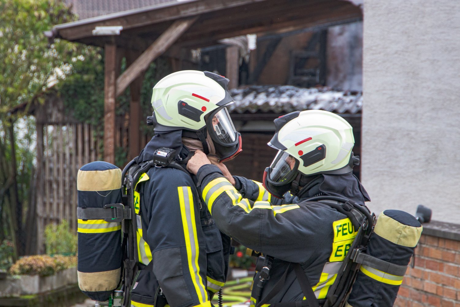 Zwei Feuerwehrleute vor dem abgebrannten Dachstuhl.