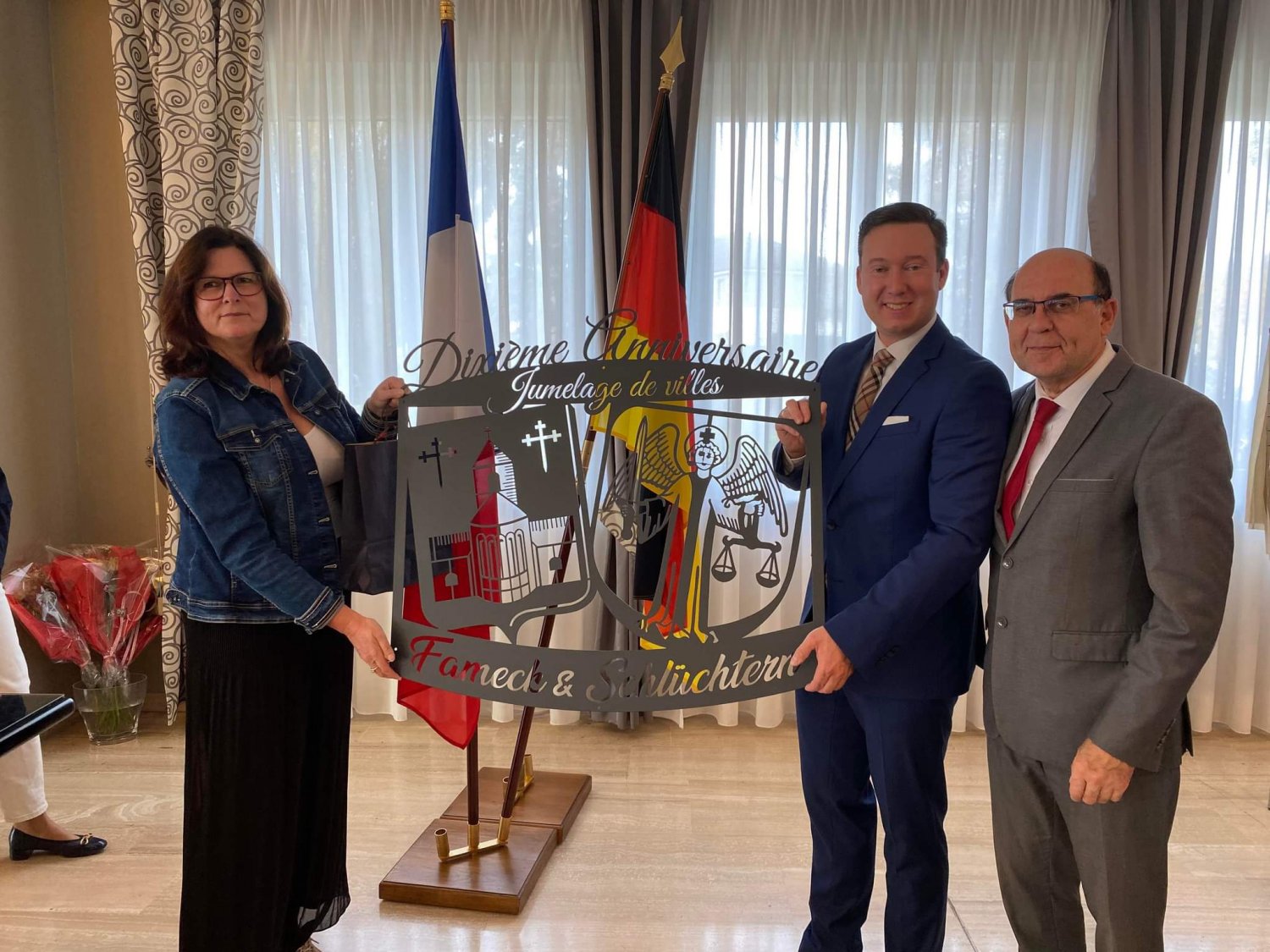 Bildunterschrift: Bürgermeister Matthias Möller und Kerstin Baier-Hildebrand übergaben als Geschenk ein großes Stahlschild an Famecks Bürgermeister Michel Liebgott (rechts).