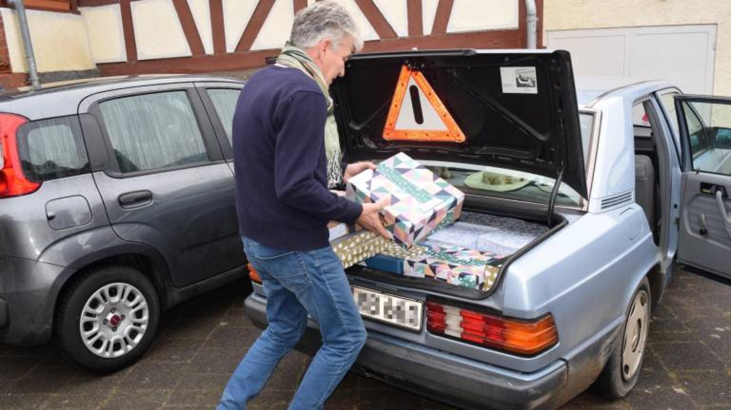 Ein ehrenamtlicher Helfer von Theologe im Ruhestand Johannes Weider lädt die Pakete ins Auto.