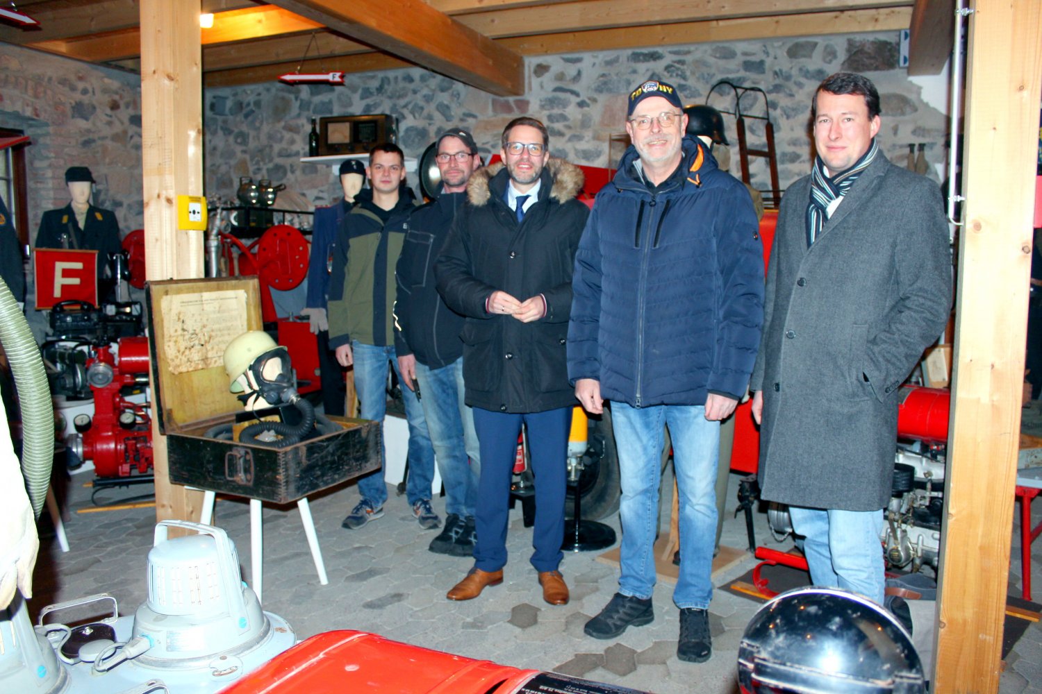 Landrat Thorsten Stolz (Dritter von links) mit Museumsleiter Süren Reifschneider (Zweiter von rechts), Bürgermeister Fabian Fehl (rechts) sowie den Vereinsmitgliedern (von links) Yannik Piston und Markus Schadt in der Sotzbacher Feuerwehrscheune.