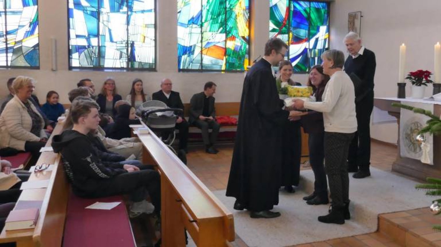 Mitglieder des Kirchenvorstandes überreichen Abschiedsgeschenke an die Pfarrer Sarah und Justus Mahn.