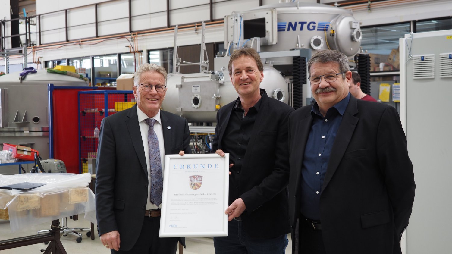 Kreisbeigeordneter Winfried Ottmann (li.) überreichte gemeinsam mit Walter Dreßbach (re.) dem Geschäftsführer der NTG Neue Technologien GmbH & Co. KG, Thomas Franz, die Auszeichnung.