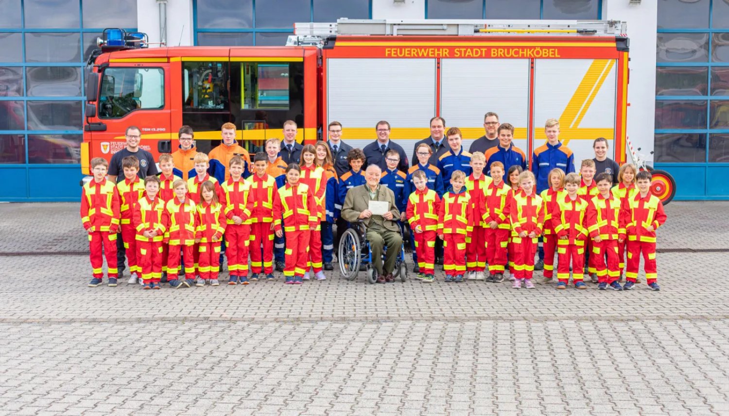 Josef Kraus (Mitte) mit der Kinderfeuerwehr (rote Bekleidung), einem Teil der Jugendfeuerwehr (blaue Bekleidung) sowie den Jugend- und Kinderfeuerwehrwarten bei der Übergabe der Spende.