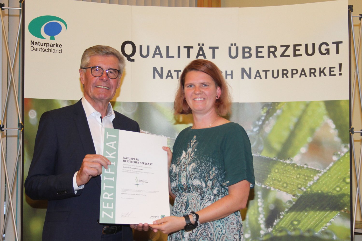 Naturpark-Geschäftsführerin Annika Ludwig nimmt das Zertifikat Qualitätsnaturpark aus den Händen des VDN-Präsidenten Friedel Heuwinkel entgegen.
