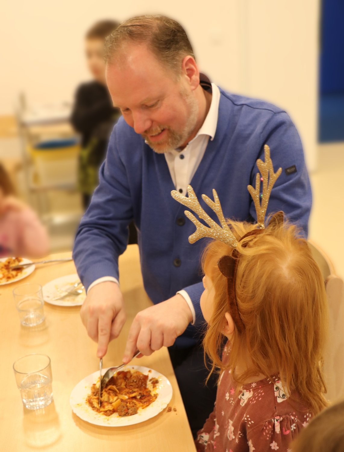 Bürgermeister Christian Litzinger genießt Lasagne in der Kita Wiesenzwerge und hilft seiner Tischnachbarin beim Zerteilen der leckeren Mahlzeit.