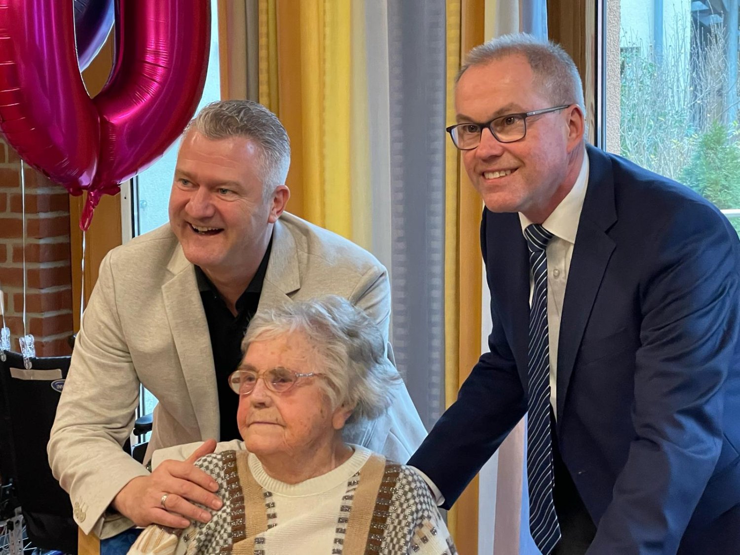 Bürgermeister Gerald Helfrich (rechts) und der Geschäftsführer der Alten- und Pflegezentren des Main-Kinzig-Kreises, Marco Maier, beglückwünschen Marie Waitz zu ihrem 100. Geburtstag.