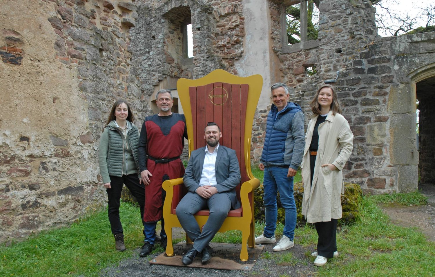 Auf und neben dem neuen Thron (v.li.): Tanja Lotz (Gemeinde Sinntal), Burgherr Thomas Dorn (Ritter Schwarzenfels e.V), Bürgermeister Thomas Henfling (Gemeinde Sinntal), Geschäftsführer Bernhard Mosbacher und Alana van Heek (beide Spessart Tourismus).