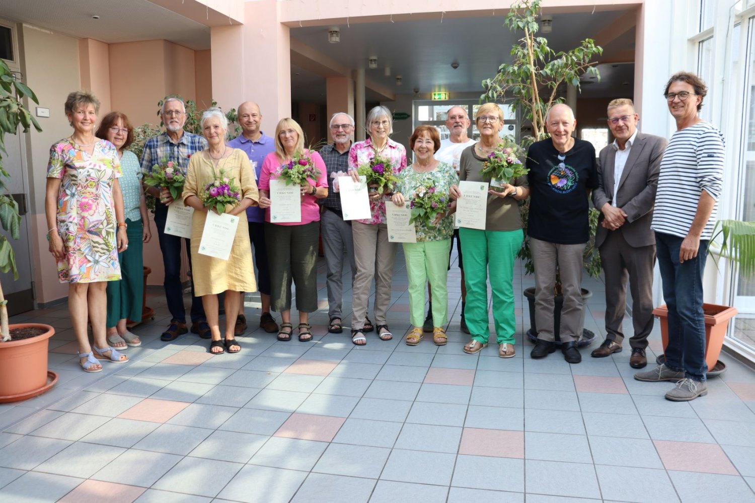 Die prämierten Gärtnerinnen und Gärtner (mit Blumen) zusammen mit den Blühbotschafterinnen und Blühbotschafter, Fachdienstleiter Andreas Amberg und Bürgermeister Stefan Erb (beide rechts im Bild).