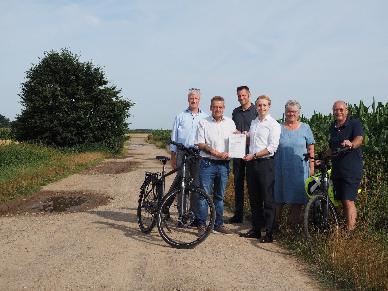 Kreisbeigeordneter Jannik Marquart übergibt Erlensees Bürgermeister und weiteren Vertretern der Stadt gemeinsam mit Elmar Sachs, Radverkehrsbeauftragter des Main-Kinzig-Kreises, den Förderbescheid für den Bau des Radwegs.