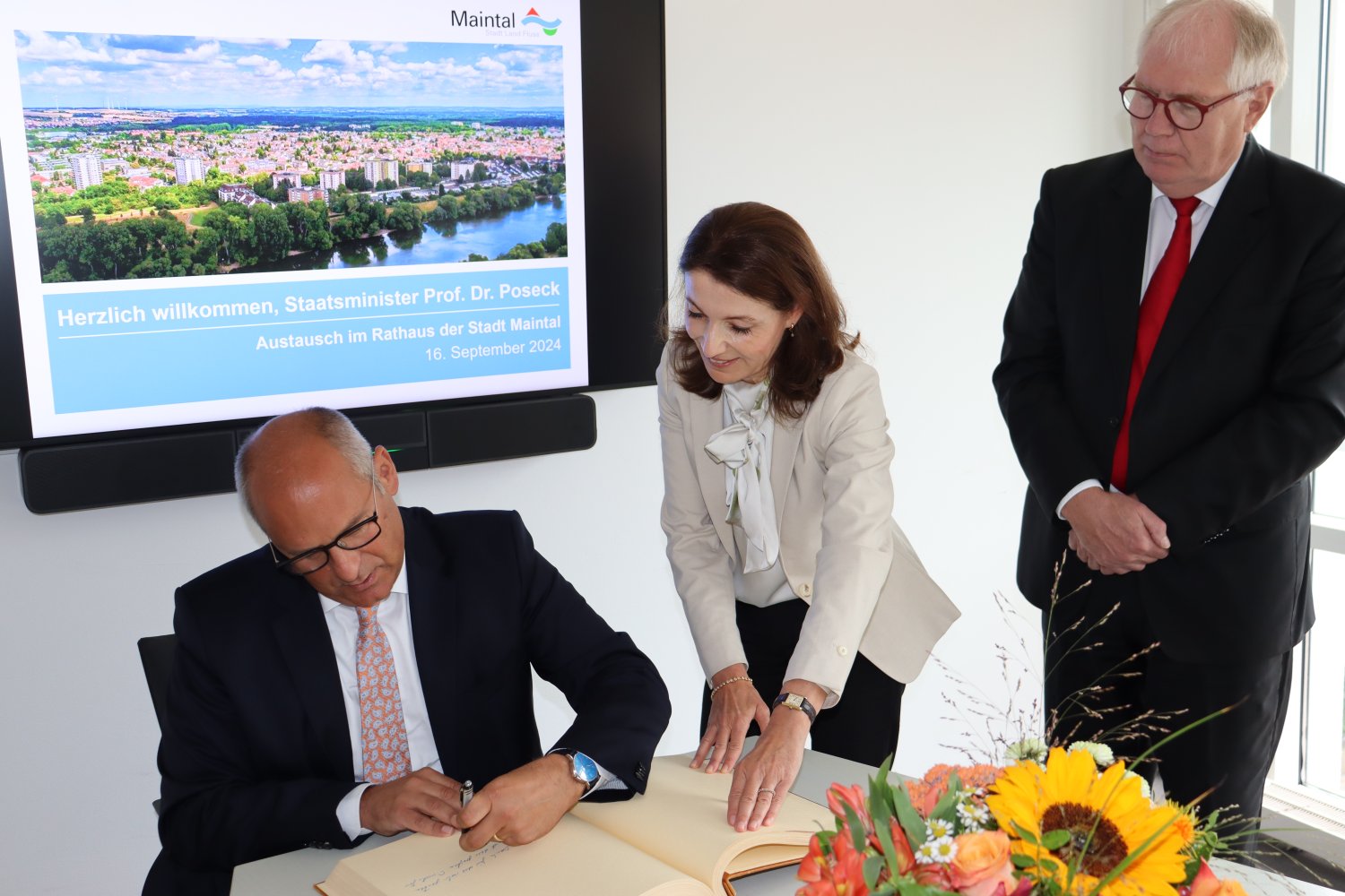 Hessens Innenminister Prof. Dr. Roman Poseck (sitzend) trug sich bei seinem Besuch im Rathaus der Stadt Maintal im Beisein von Bürgermeisterin Monika Böttcher und Erstem Stadtrat Karl-Heinz Kaiser ins Goldene Buch der Stadt ein.