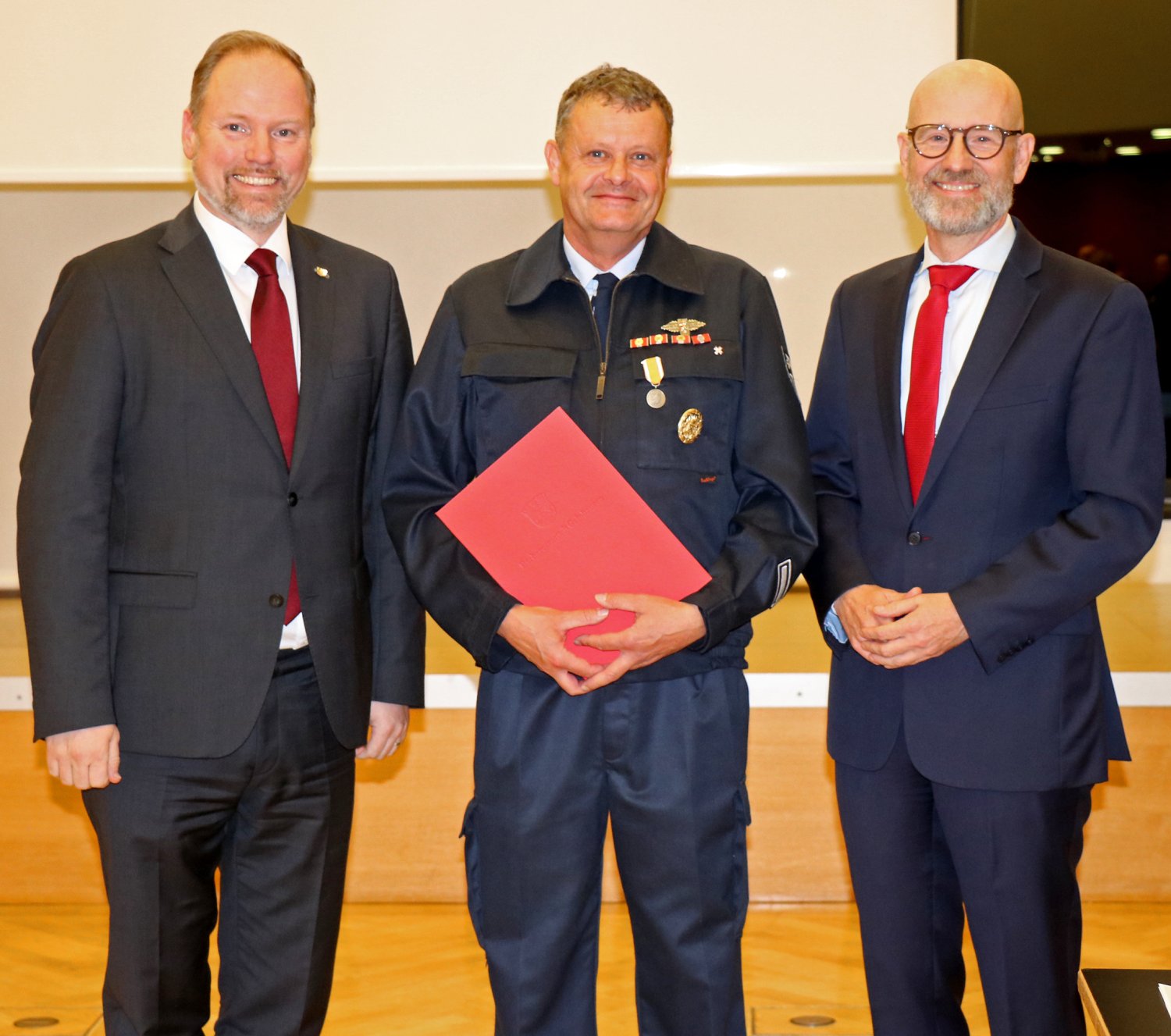 Mit Stolz und Dankbarkeit: Bürgermeister Christian Litzinger (links) und Stadtverordnetenvorsteher Dr. Peter Tauber übergeben Rettungsmedaille und Urkunde an Brandmeister Frank Weigelt (Mitte).   