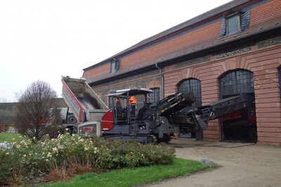 Ein ungewöhnliches Bild vor und in der Orangerie von Schloss Philippsruhe: Per Mischmaschine wird Asphalt über ein Förderband und ein vorübergehend ausgebautes Türelement ins Innere verbracht.