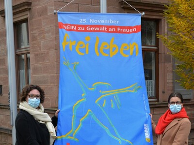 Erste Kreisbeigeordnete Susanne Simmler (links) mit Grit Ciani, Frauenbeauftragte des Main-Kinzig-Kreises mit der Fahne, die unter dem Motto „Frei leben ohne Gewalt“ am Kino „Pali“ in Gelnhausen auf den Aktionstag aufmerksam macht.