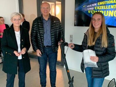Dörte-Christin Lange und Torsten Priemer (beide Kreissparkasse Schlüchtern) überreichen Paulina Hildmann den Hauptpreis: einen E-Scooter.